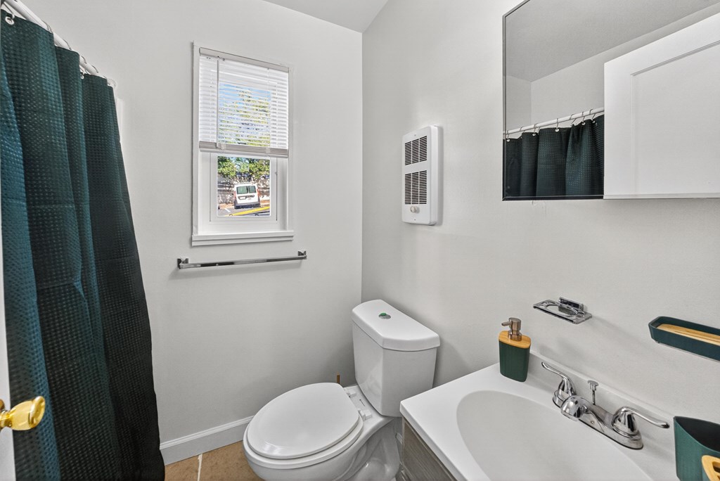 A bathroom with a toilet, sink, and window.