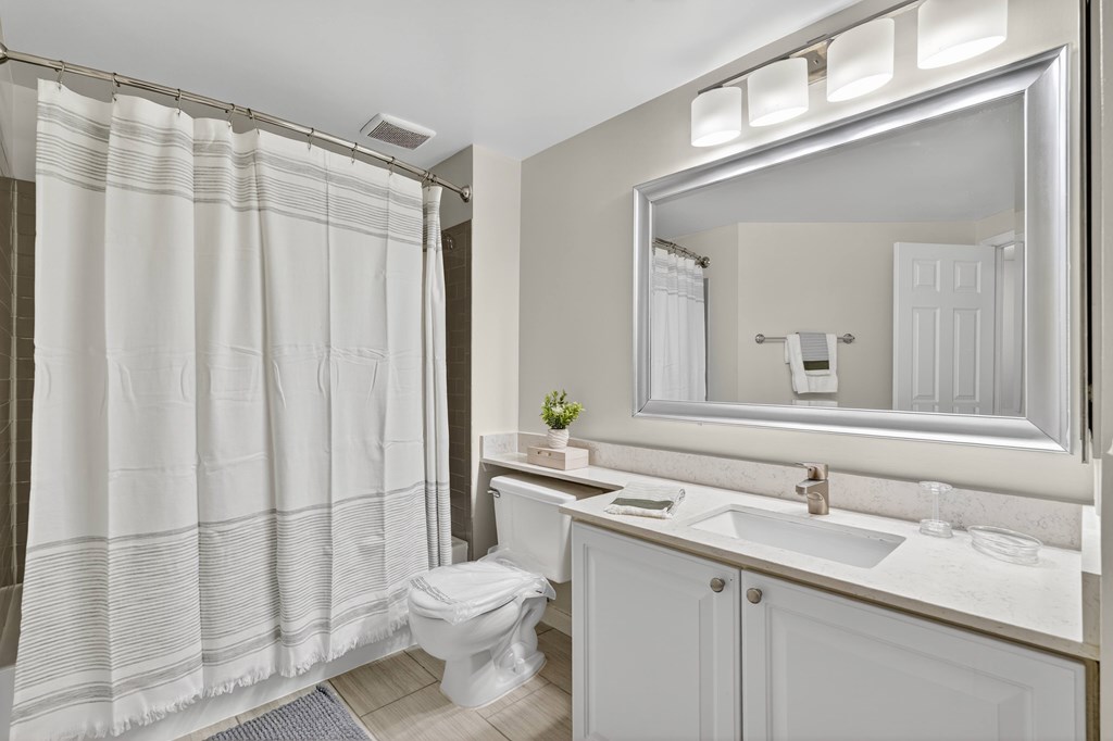 A white bathroom with a toilet, sink, and shower curtain.