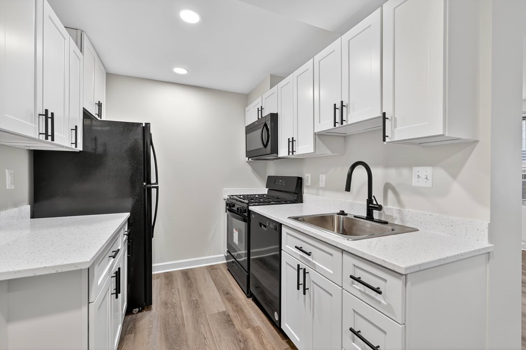 A kitchen with black appliances and white cabinets.
