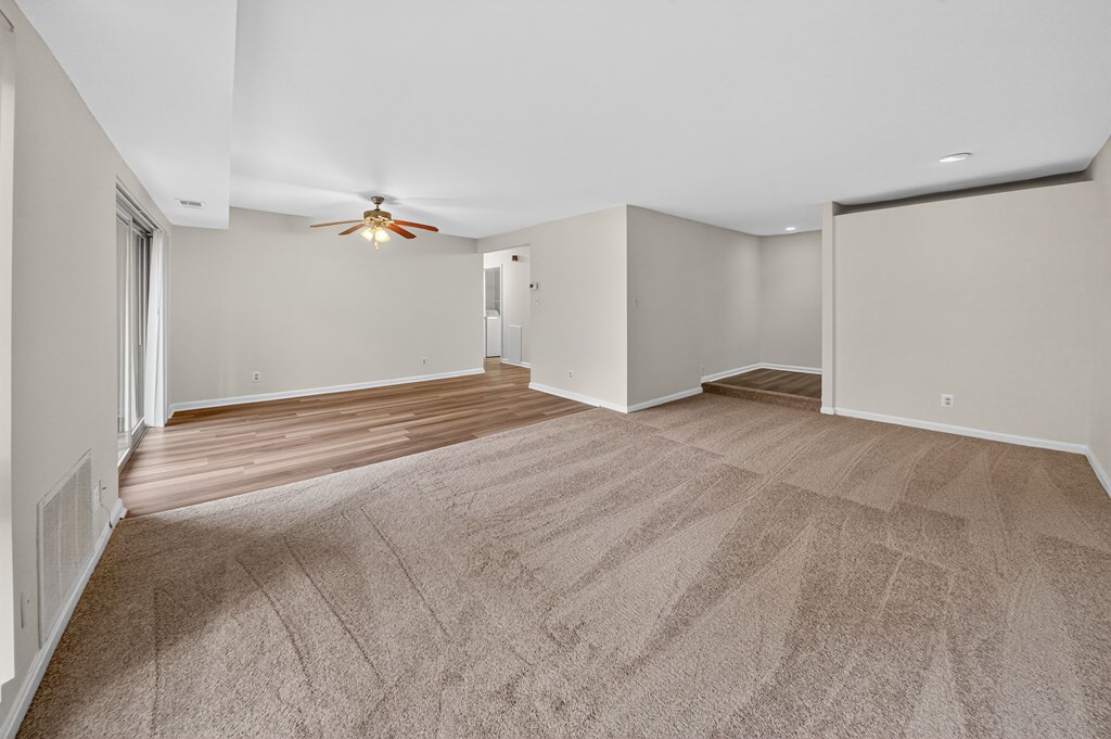 A room with a carpeted floor and a ceiling fan.