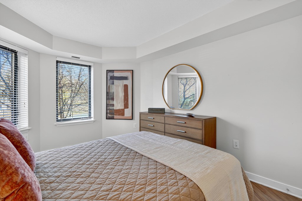 A bedroom with a large bed, a dresser, and a mirror.