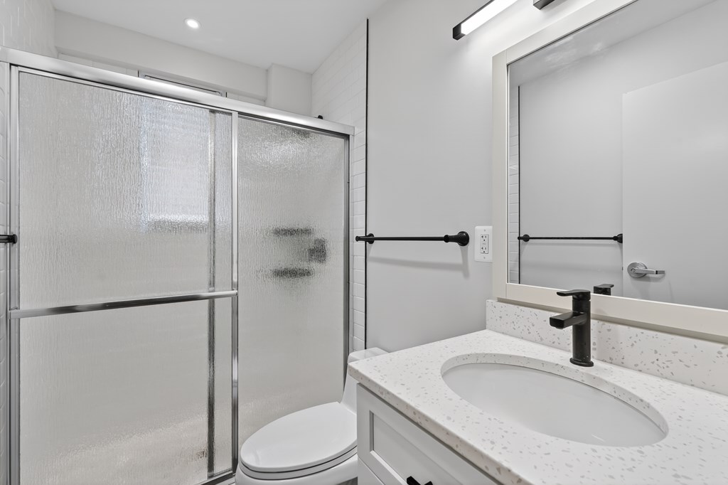 A white bathroom with a toilet, sink, and shower.