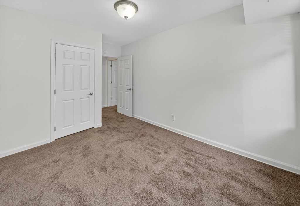 A room with carpeted floor and two doors.
