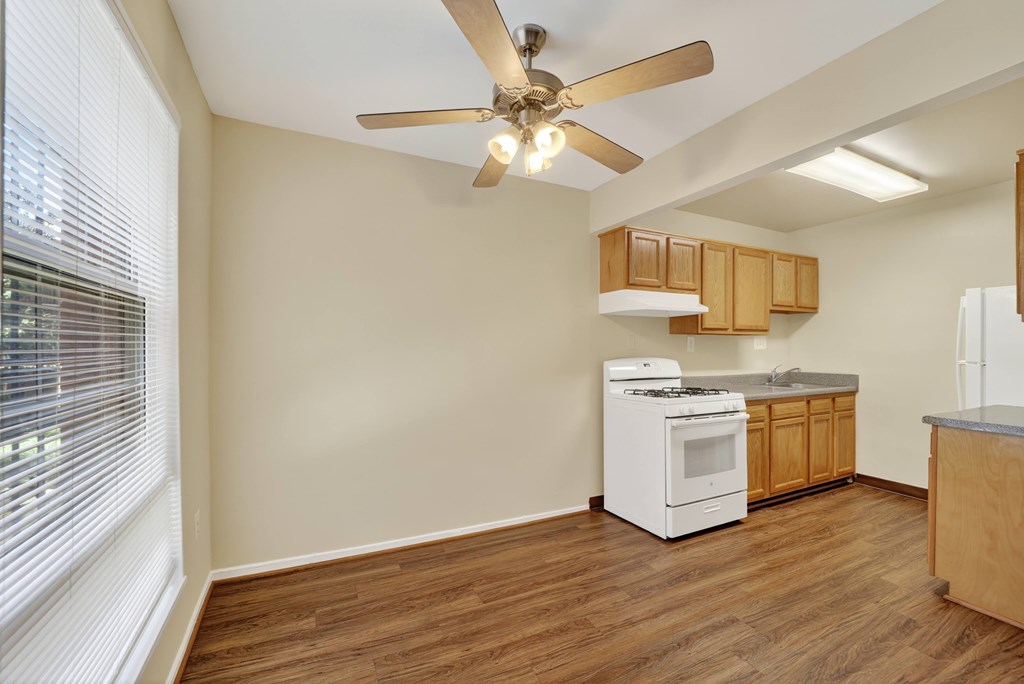A kitchen with a white dishwasher and a white stove with wooden cabinets.