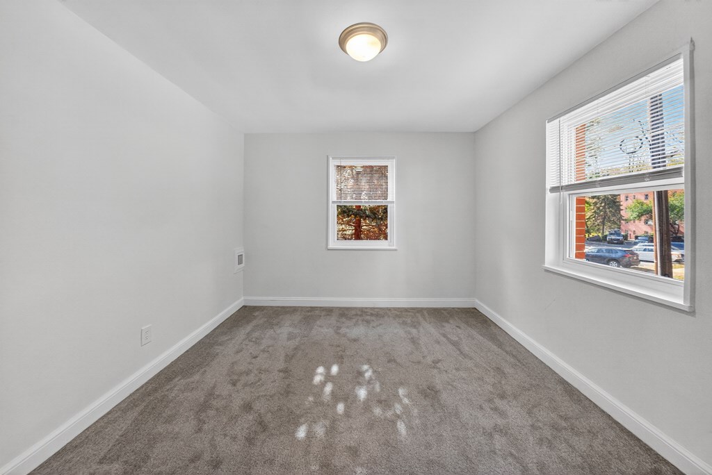 A room with a grey carpet and a picture frame on the wall.