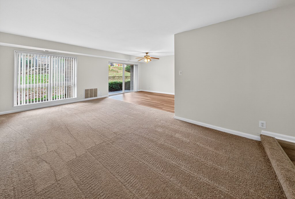 A room with a carpeted floor and a ceiling fan.