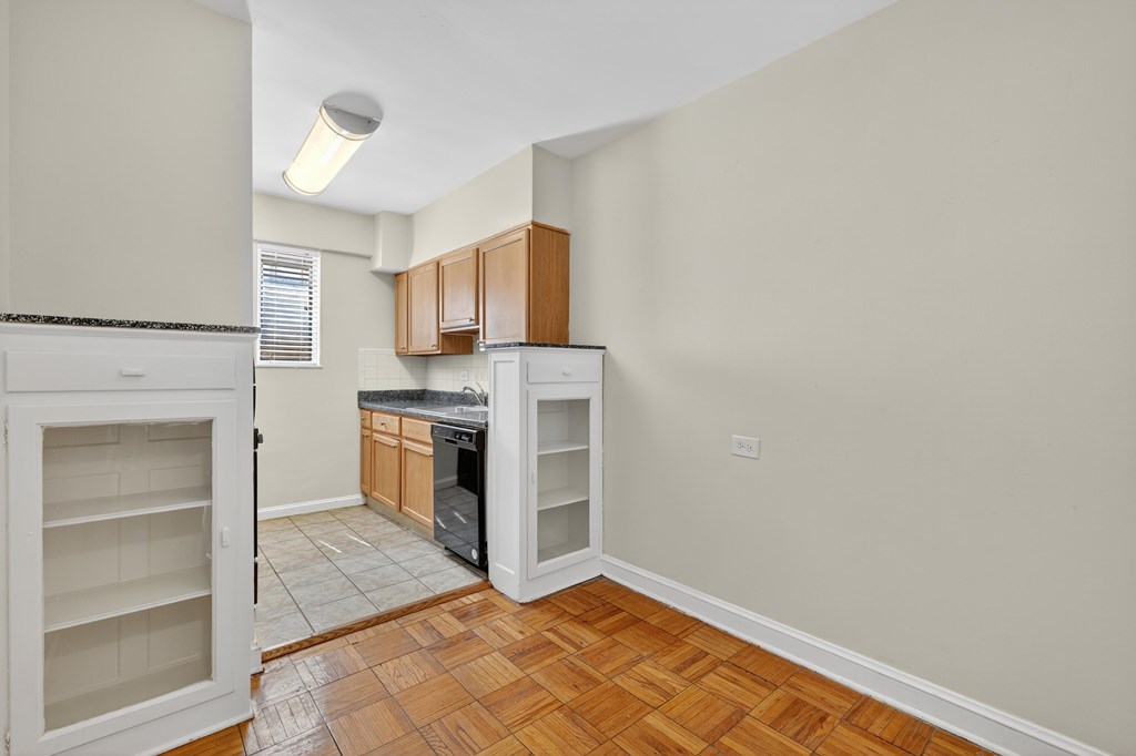 A kitchen with a black counter top and wooden cabinets.