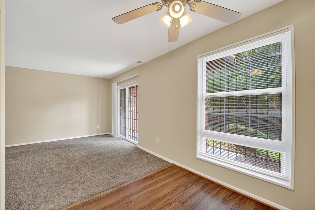 A room with a ceiling fan and a window with blinds.