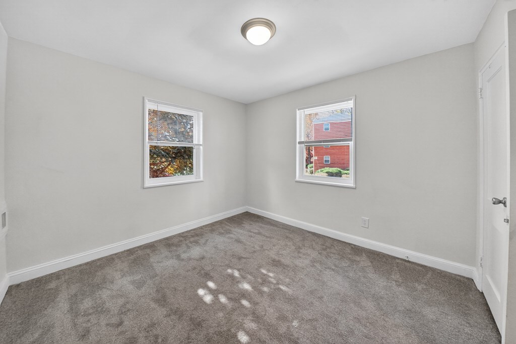 A room with a grey carpet and two pictures on the wall.