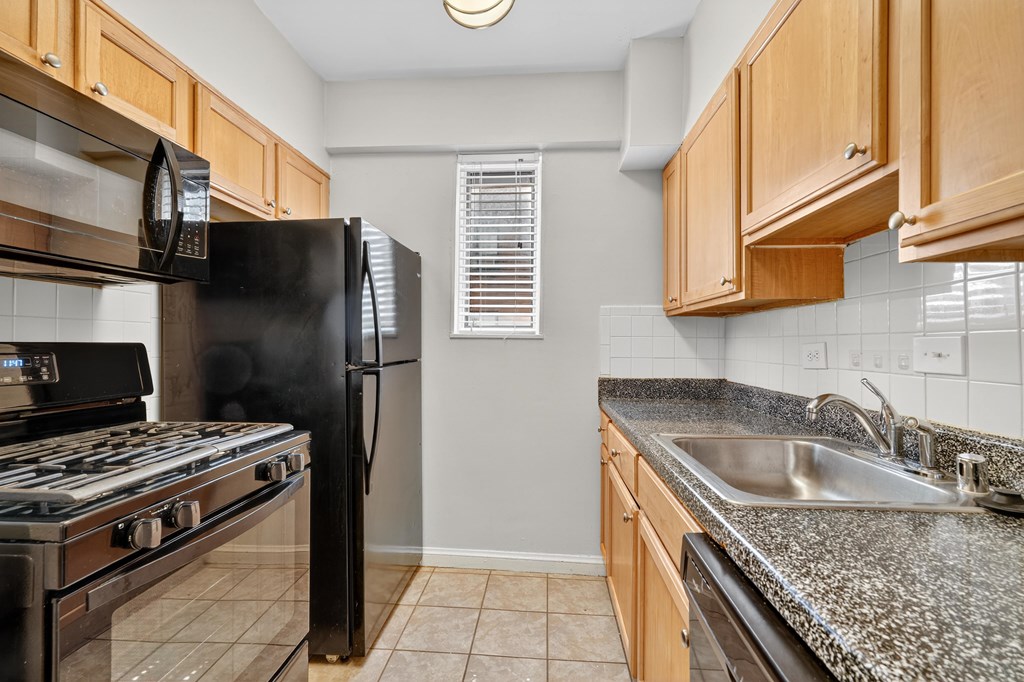 A kitchen with black appliances and wooden cabinets.