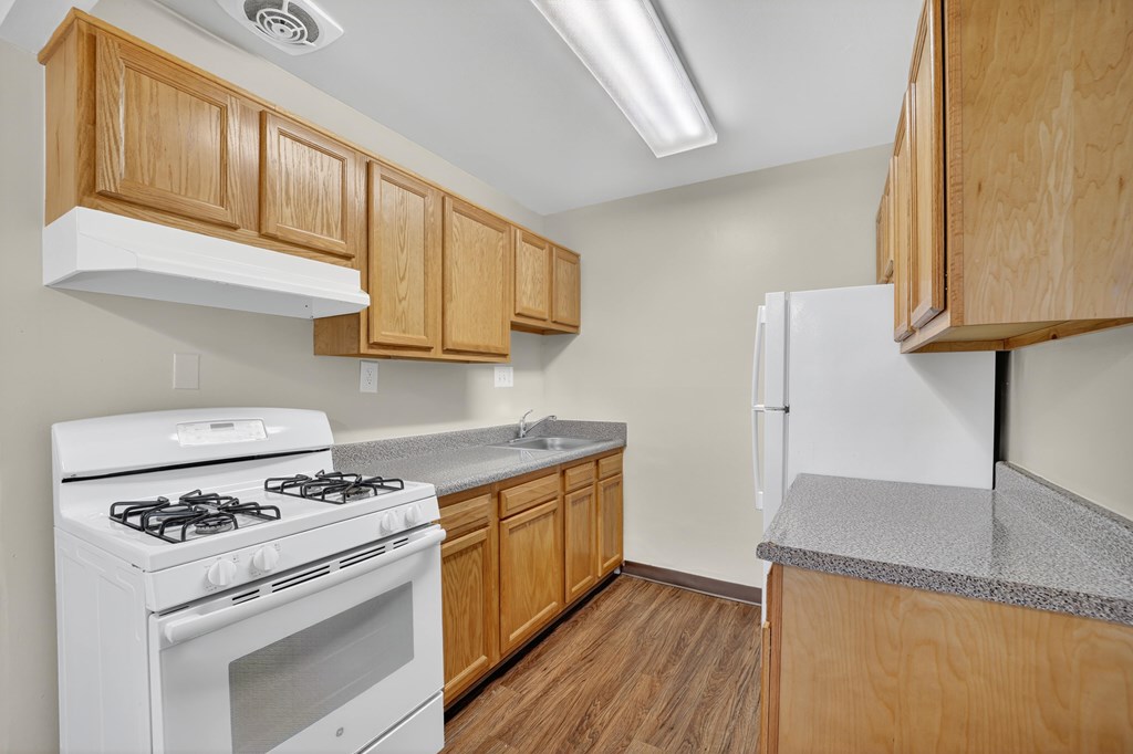 A kitchen with a white stove and wooden cabinets.