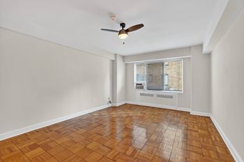 A room with a ceiling fan and wooden flooring.
