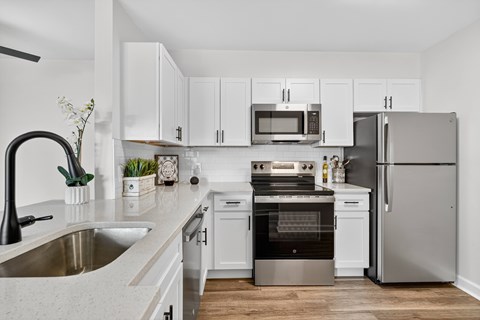 A modern kitchen with white cabinets and stainless steel appliances.