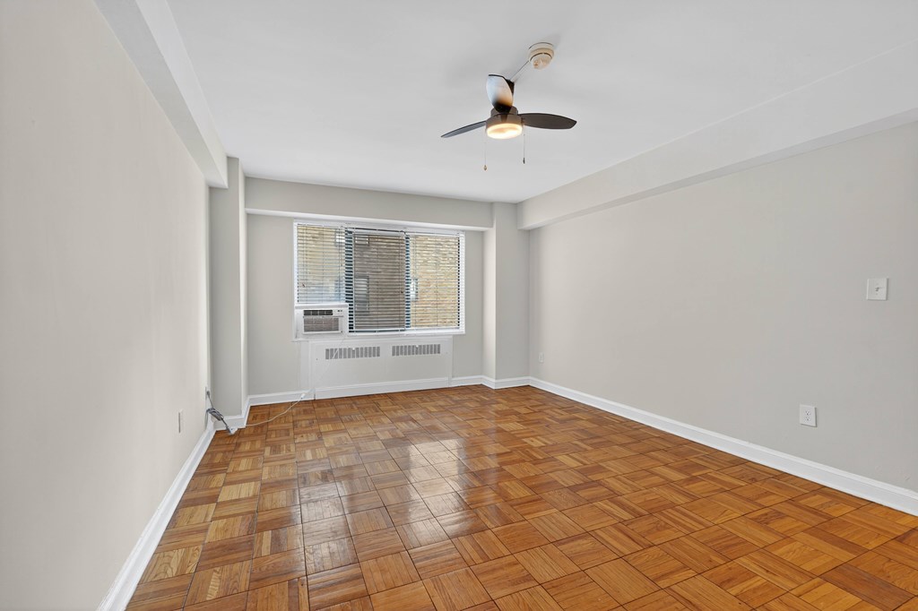 A room with a ceiling fan and a window with blinds.