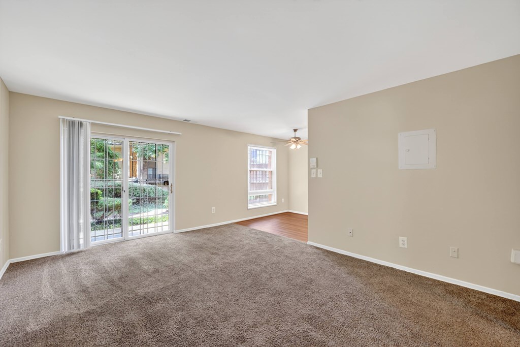A room with a carpeted floor and a sliding glass door leading to a patio.