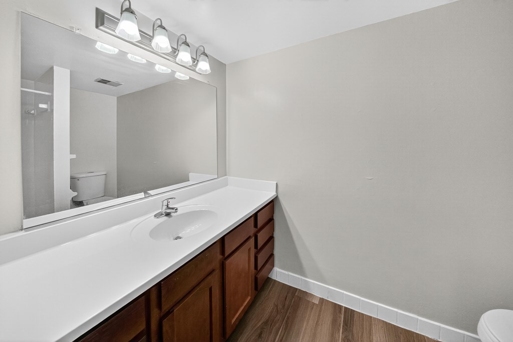A bathroom with a white countertop and brown drawers.