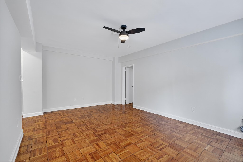A room with a ceiling fan and wooden flooring.