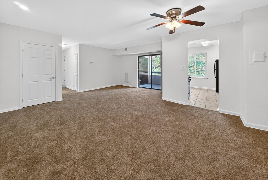 A room with a ceiling fan and carpeted floor.