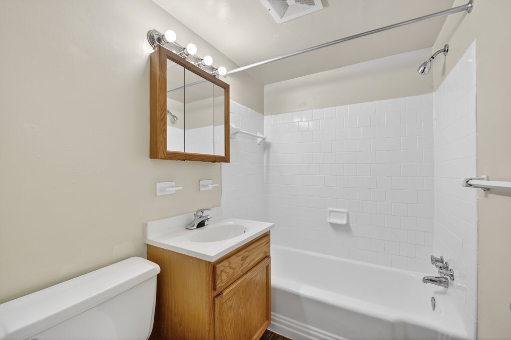 A bathroom with a white tub, sink, and mirror.