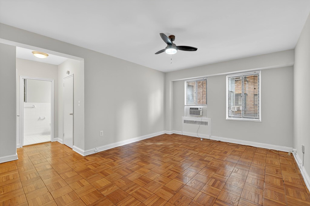 A room with a ceiling fan and wooden flooring.