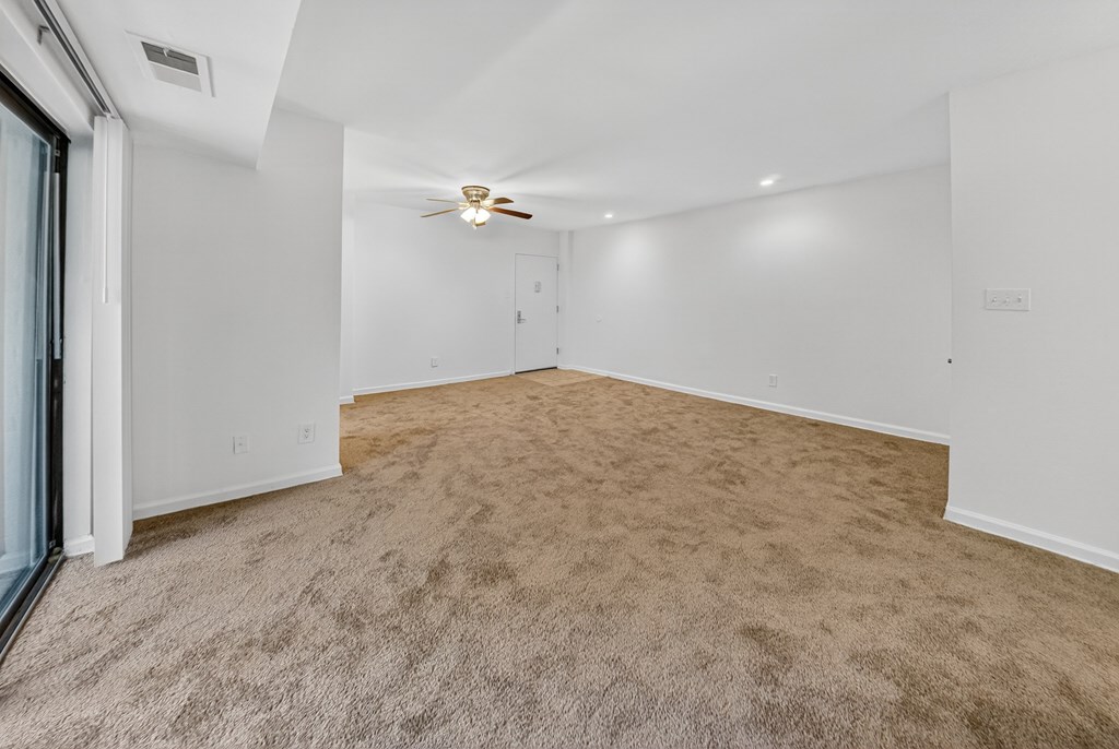 A room with a carpeted floor and a ceiling fan.