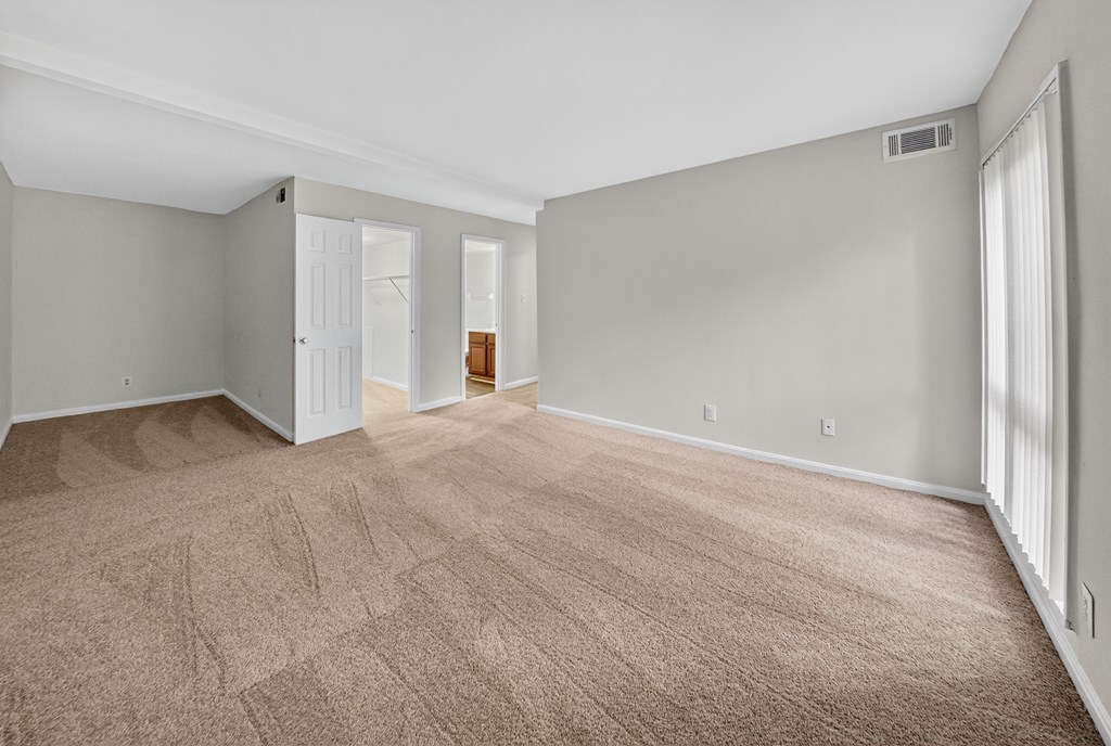 A room with a carpeted floor and a doorway leading to another room.