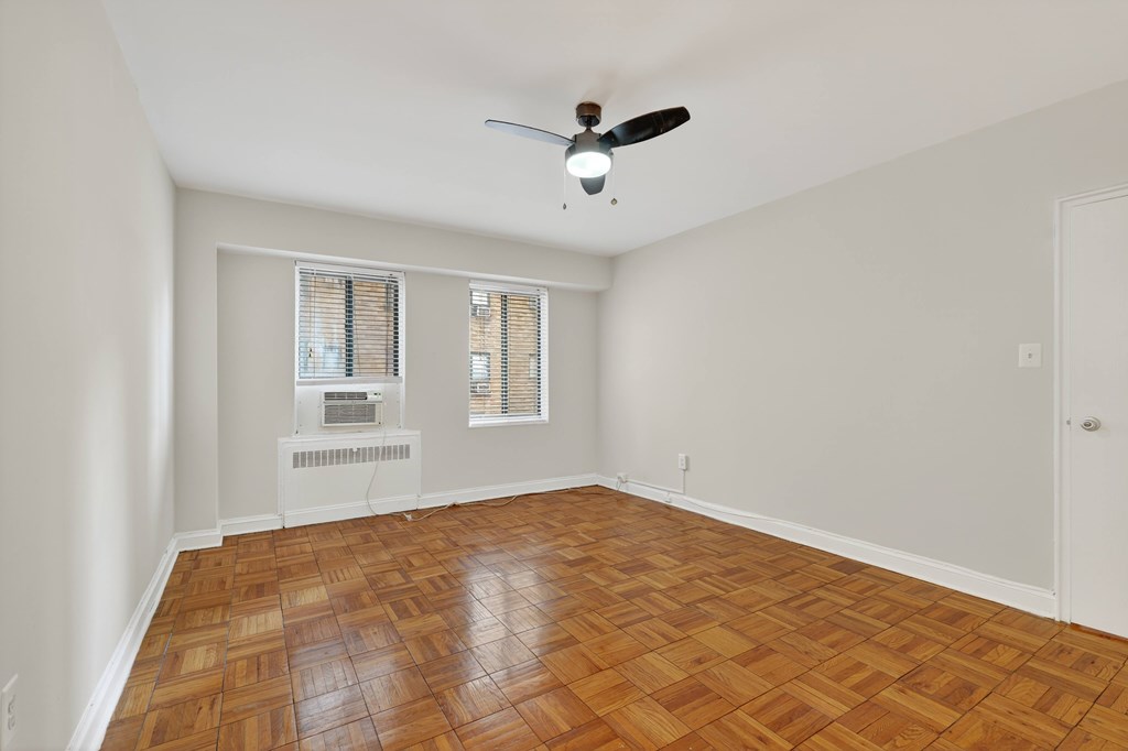 A room with a ceiling fan and a radiator on the wall.