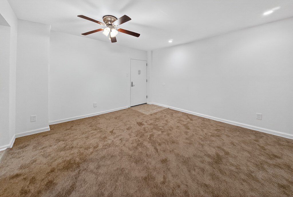 A room with a ceiling fan and carpeted floor.
