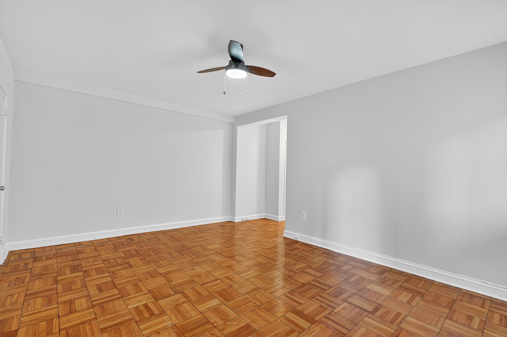 A room with a ceiling fan and wooden flooring.