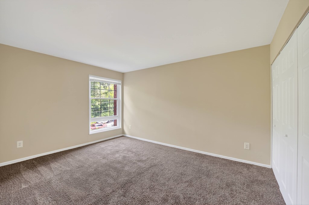 A room with a carpeted floor and a window.