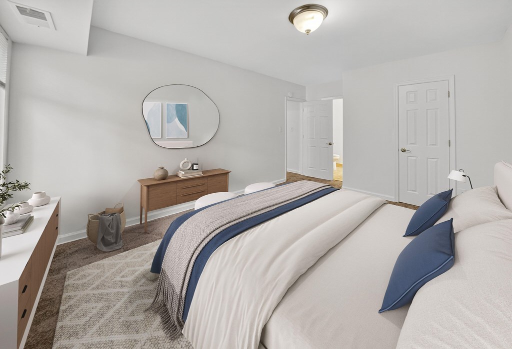 A bedroom with a large bed and a mirror on the wall.