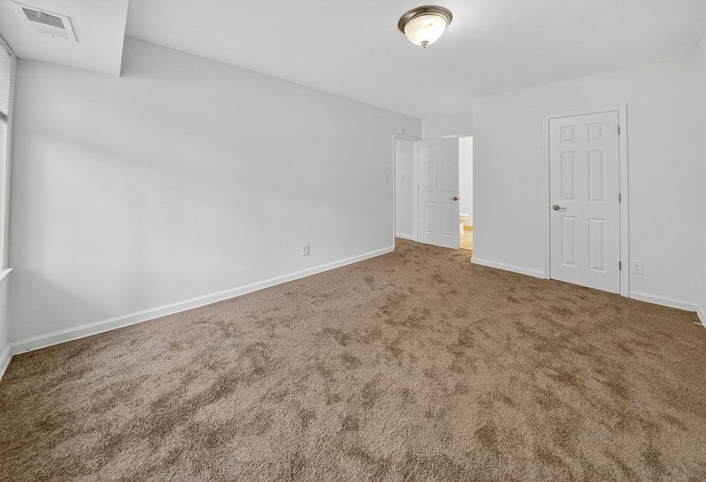 A room with a carpeted floor and two doors.
