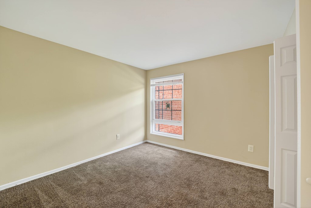 A room with a window and a carpeted floor.