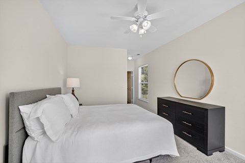 A classic style bedroom with a bed, dresser, and ceiling fan.