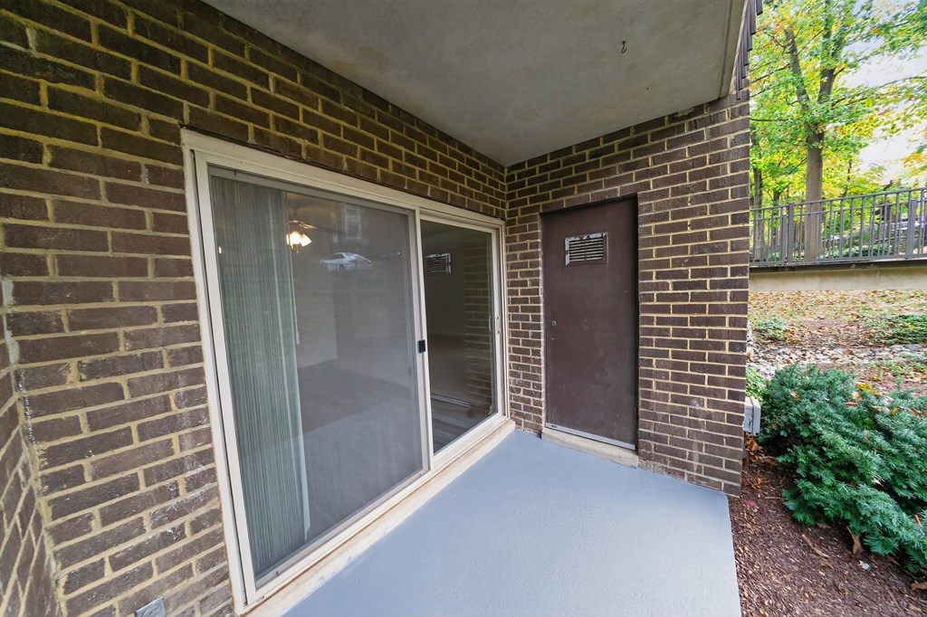 A patio area with a sliding glass door and a brick wall.