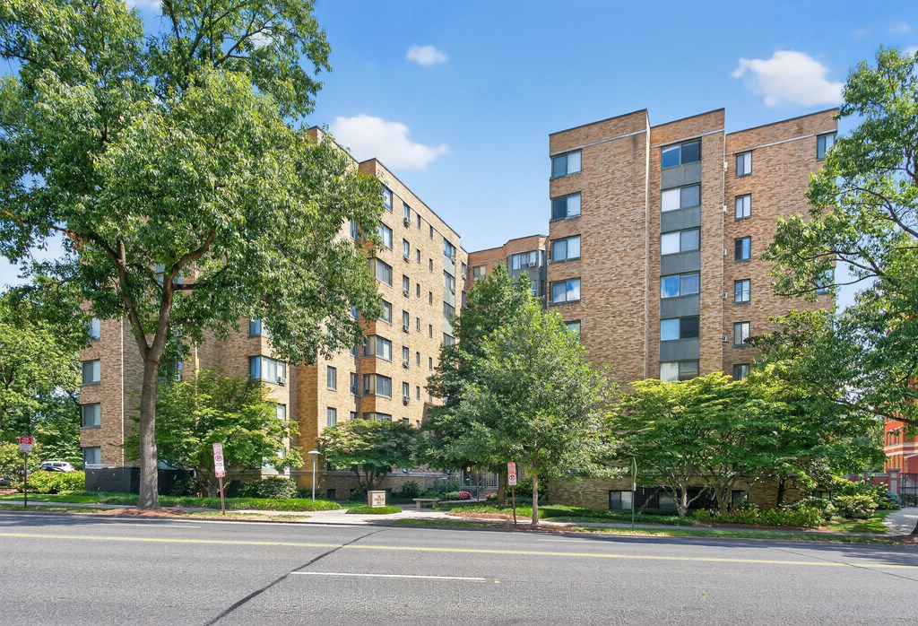 A street view of a residential area with apartment buildings and trees.