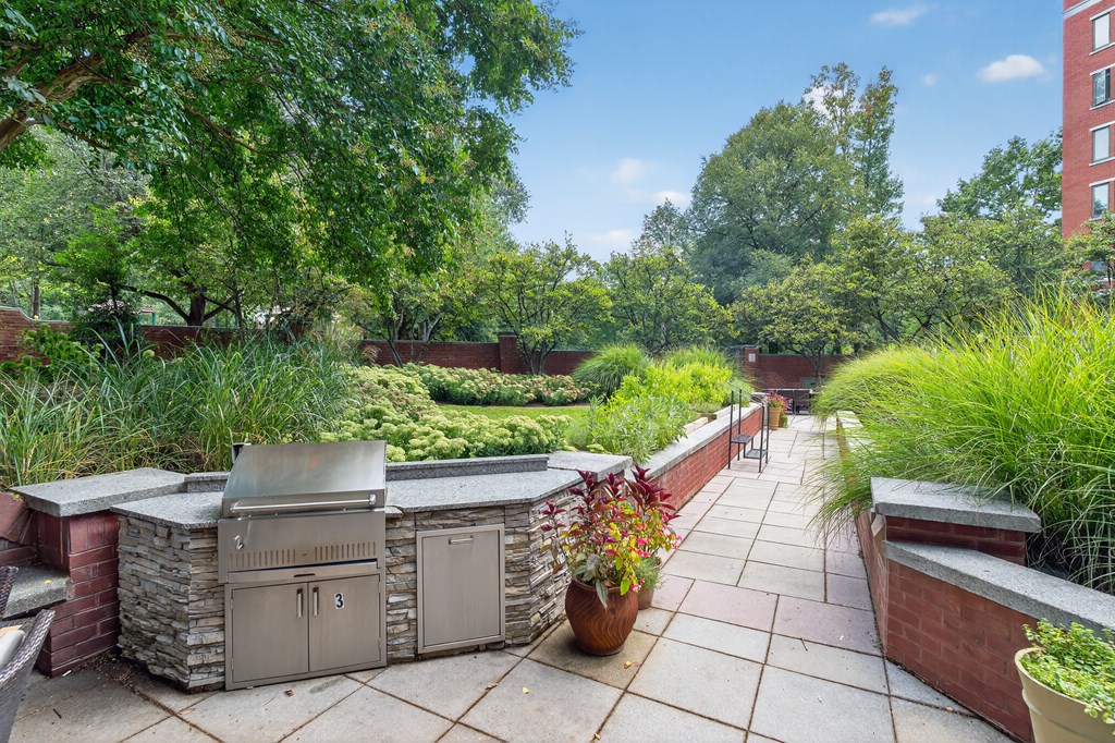 A patio with a grill and potted plants.