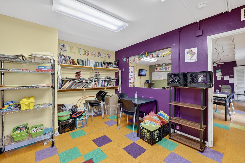 A library with purple walls and a variety of books on shelves.