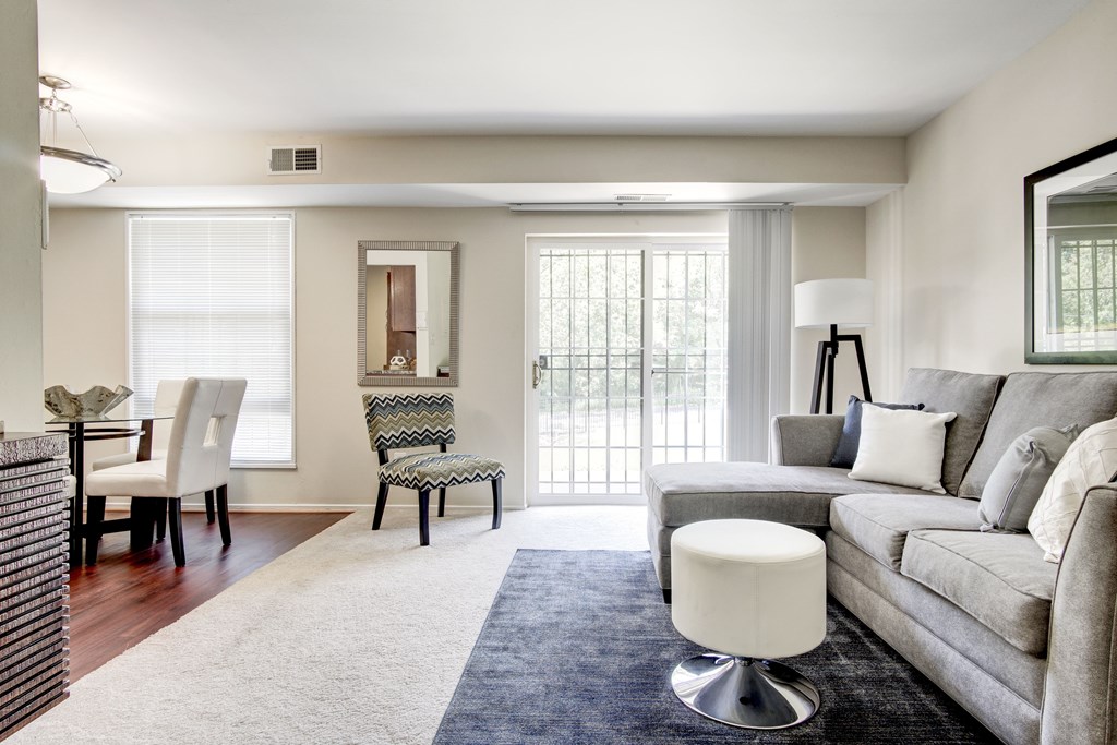 A living room with a grey couch, a white chair, and a white ottoman.