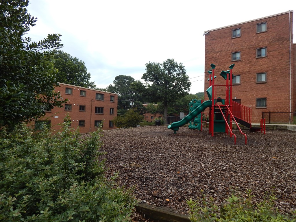 A playground with a green slide and red structure.