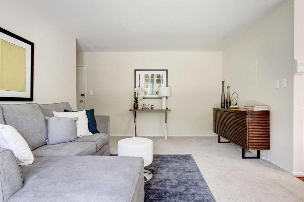 A living room with a grey couch and a white ottoman.