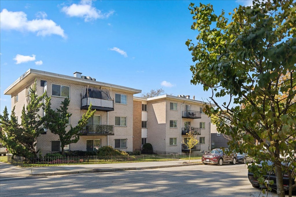 a street view of an apartment building with a car parked in front