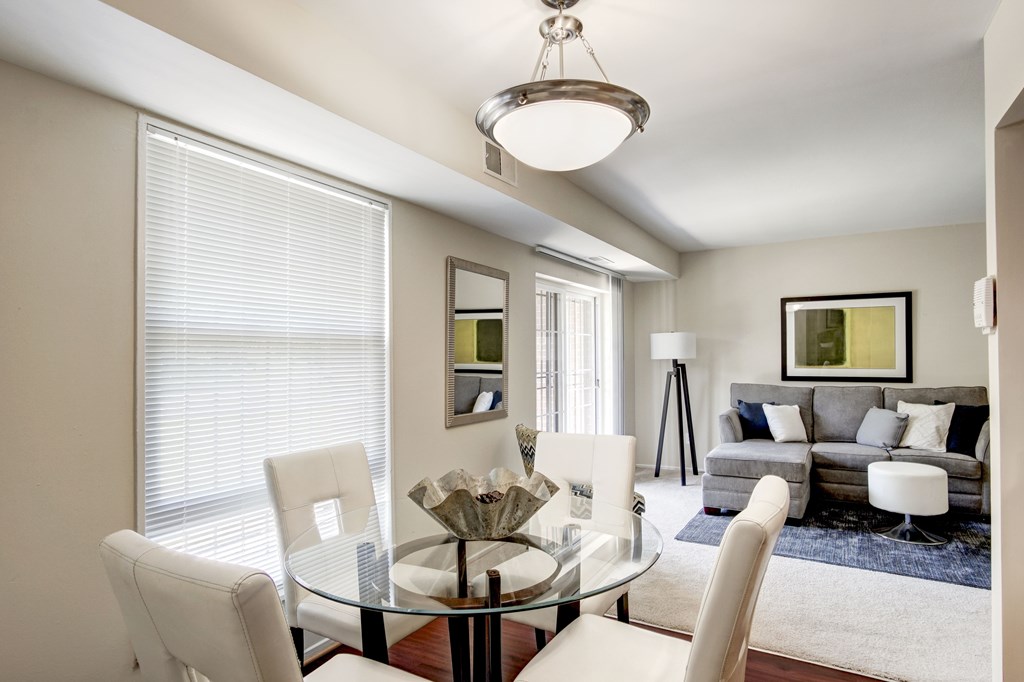 A modern dining room with a glass table and white chairs.