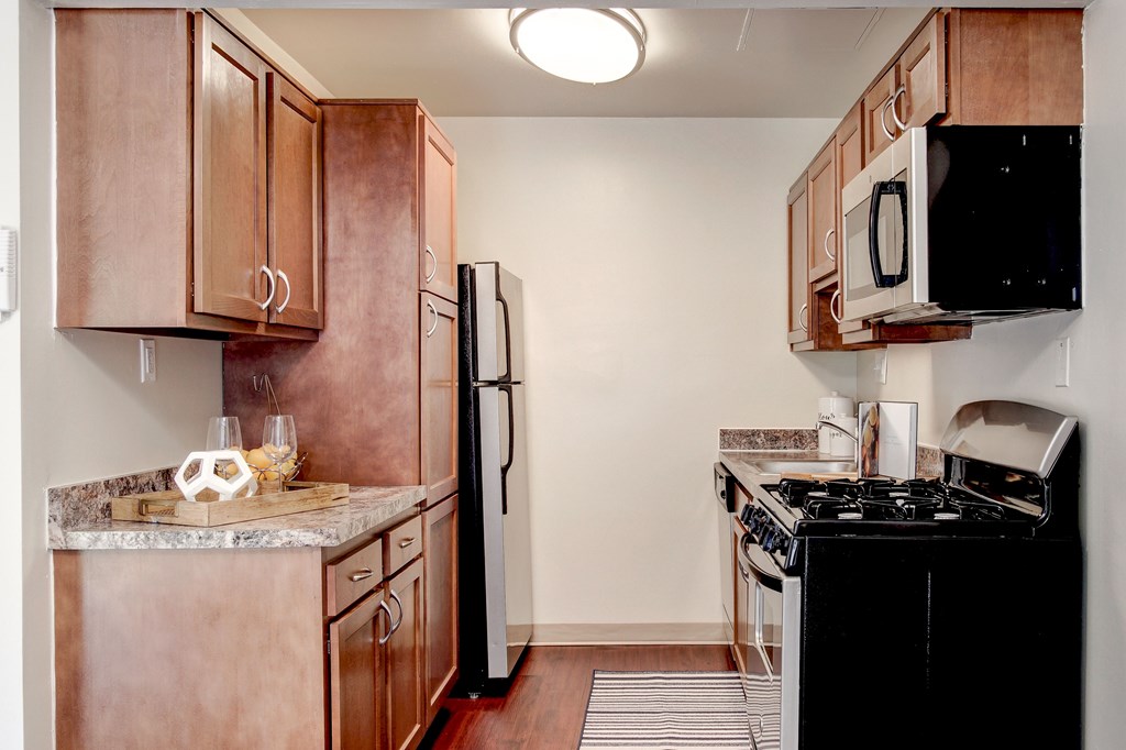 A kitchen with brown cabinets and black appliances.
