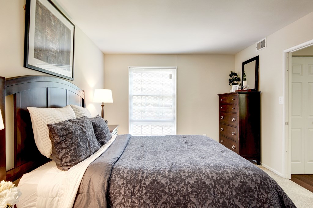 A bedroom with a large bed and a painting on the wall.