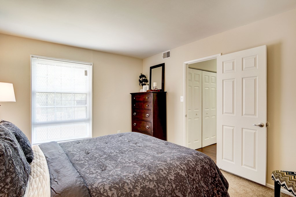 A bedroom with a bed, dresser, and mirror.
