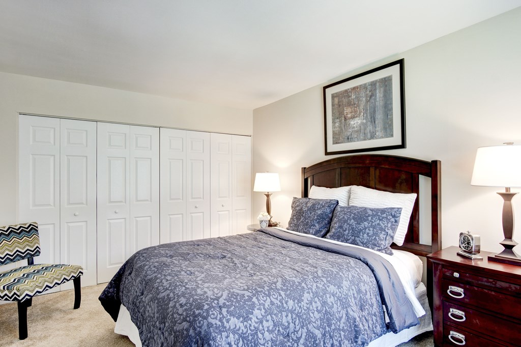 A bedroom with a bed, nightstand, and chair.