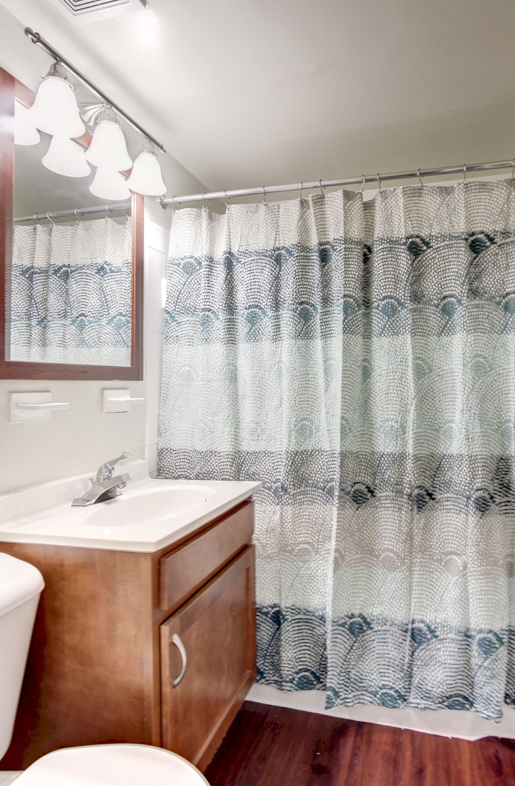 A bathroom with a white sink and a brown cabinet.