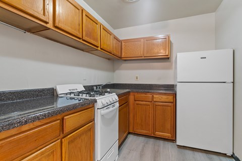 A kitchen with a white fridge, white stove and wooden cabinets.