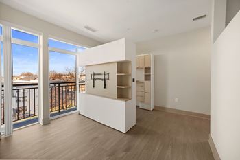 A room with a white cabinet and a balcony with a view of houses.